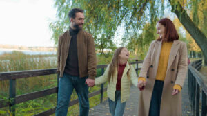 Family walking together on a wooden bridge during autumn, representing a happy family scenario, ideal for child custody modification discussions.