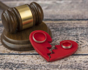 Gavel and broken heart symbolizing fault vs no-fault divorce, with wedding rings on the broken heart