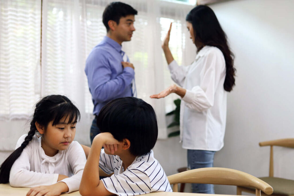 Children sitting calmly while parents argue, representing the emotional impact of divorce and the role of a Guardian Ad Litem in child custody cases