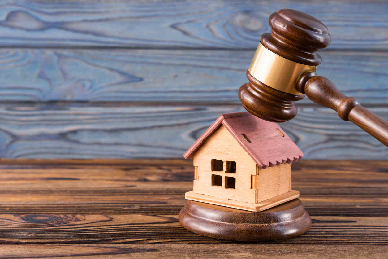 Gavel placed on a wooden house model, symbolizing property division in legal cases involving unmarried couples.