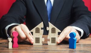 Divorce and property division concept with wooden house puzzle pieces and family figures separated by lawyer