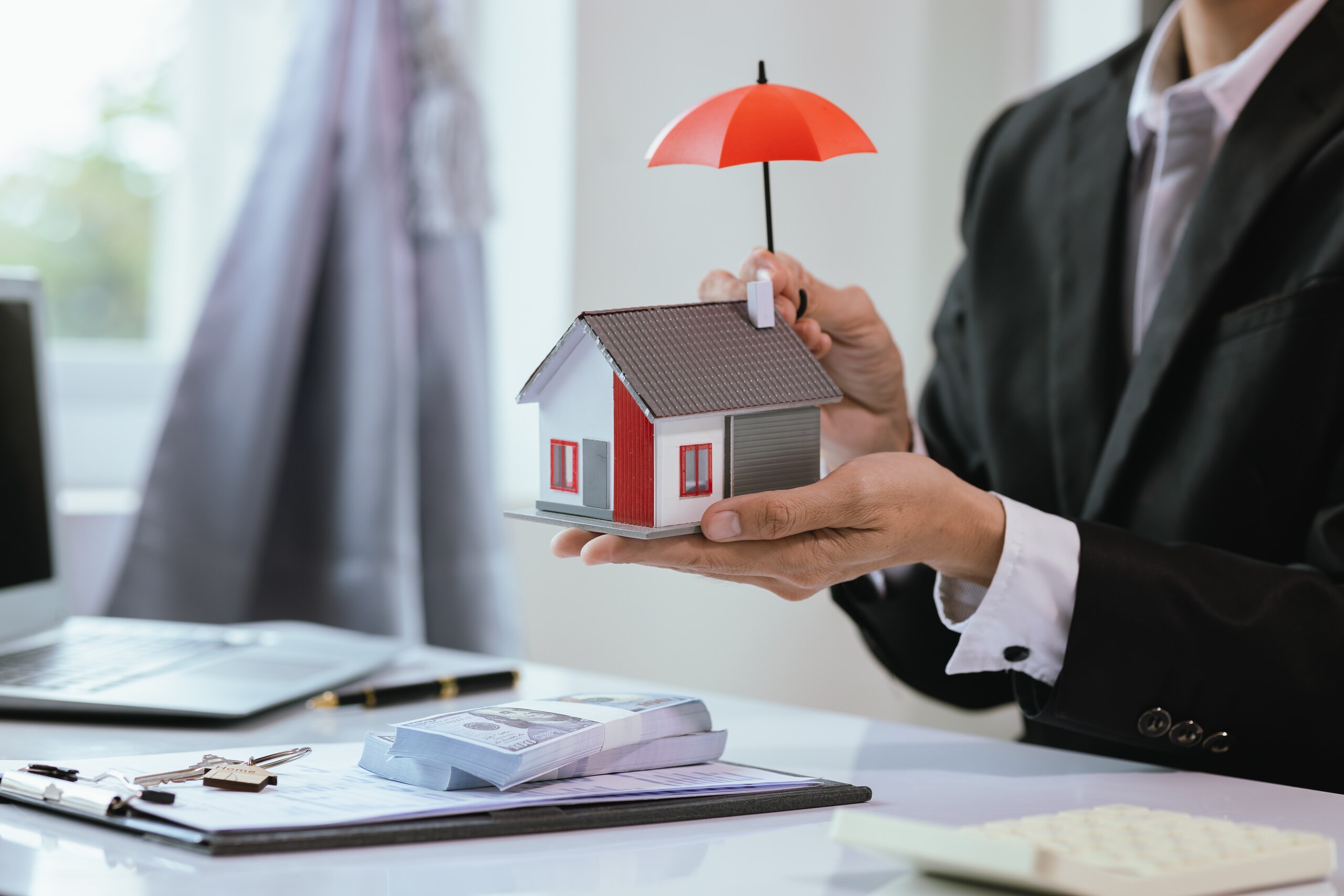 Lawyer holding a small house model under a protective red umbrella for Kansas City real estate quiet title attorneys.